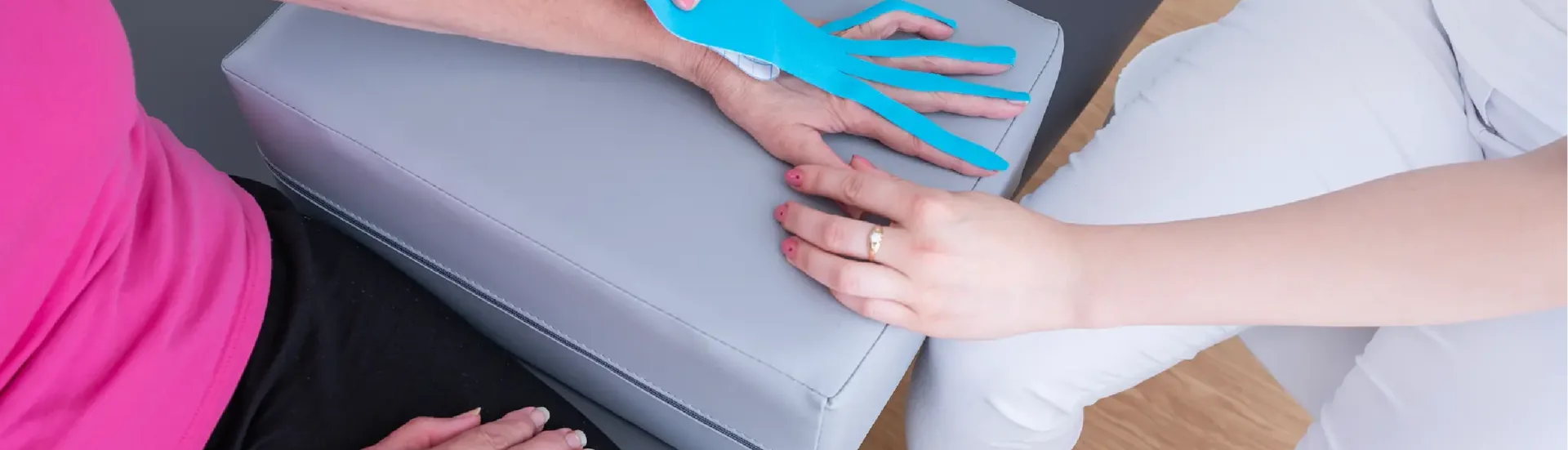 Terapeutka aplikująca kinesiotaping na rękę pacjentki