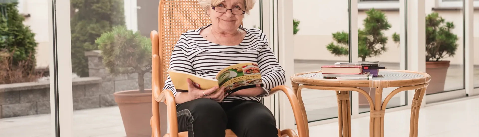 Seniorka czytająca książkę na tarasie ośrodka